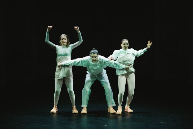 Drei Spielerinnen stehen nebeneinander. Alle tragen weisse, enge Kleidung. Die Person in der Mitte ist nach vorne gebückt und hält die beiden Spielerinnen links und rechts von ihr zurück.